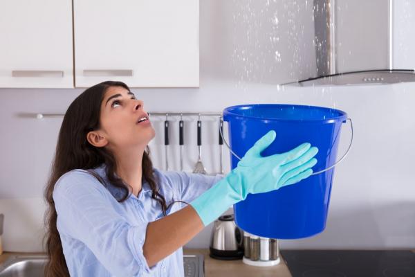 Women Holding A Blue Bucket Due To Roof Leakage