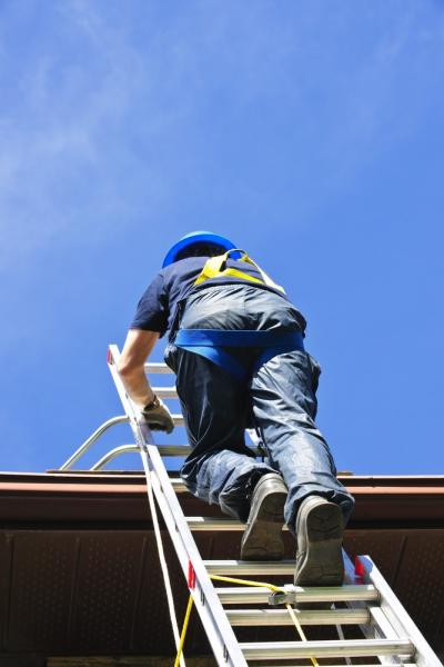 Worker With Safety Harness Climbing To The Roof