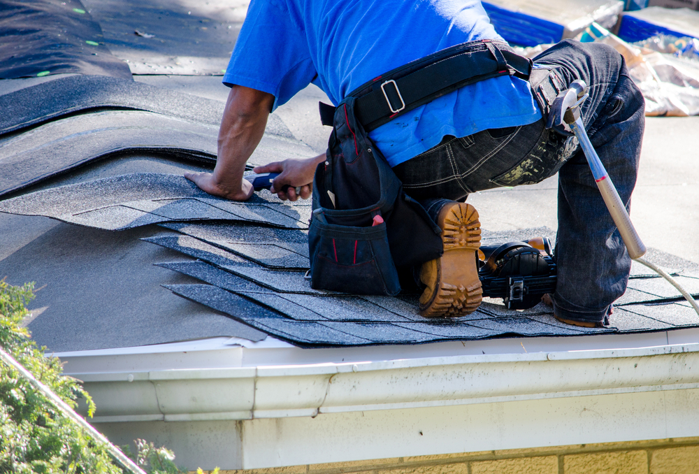 A worker replaces tiles on the roof of a home